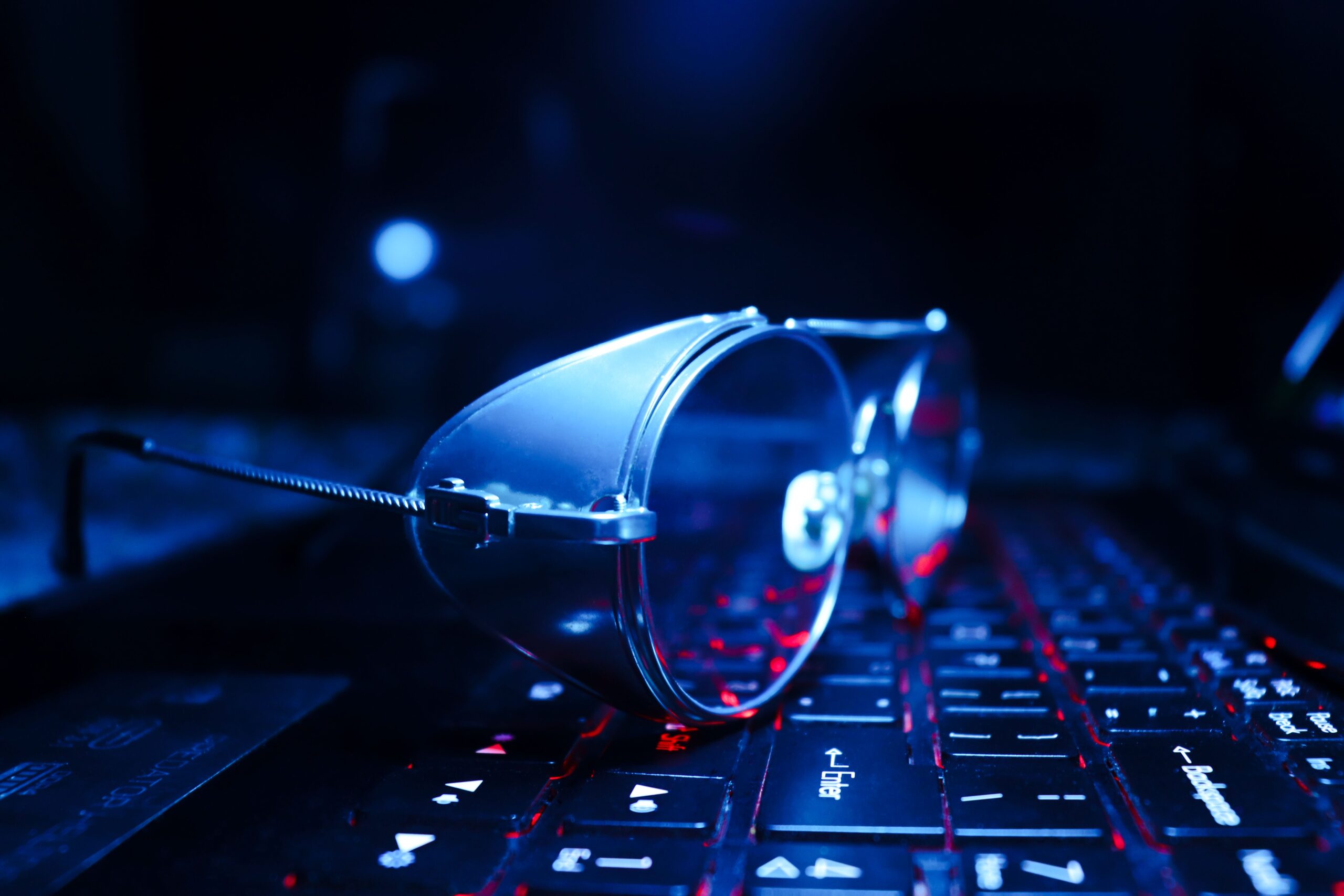 Close-up of eyeglasses on a glowing laptop keyboard, symbolizing technology and work.
